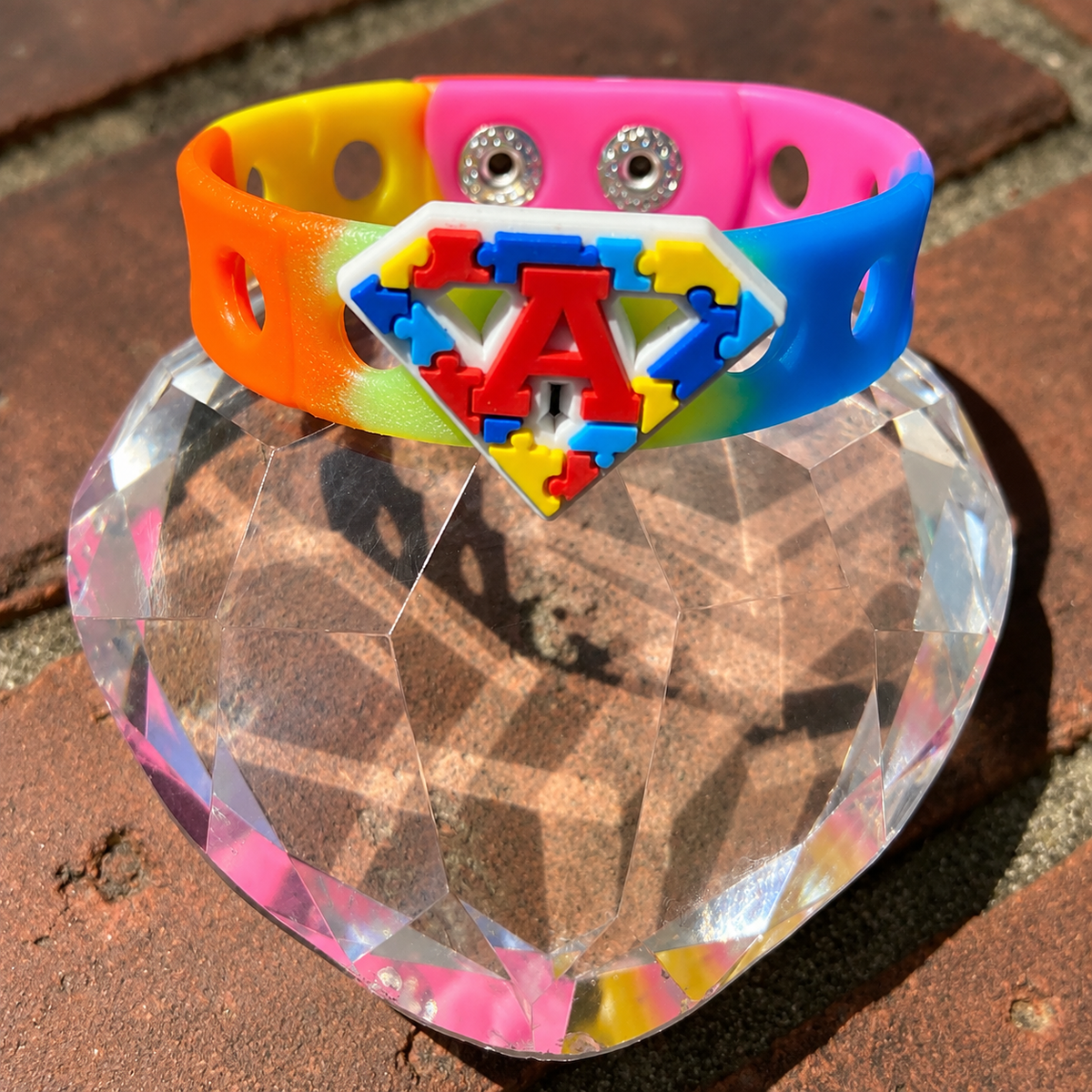 Celebrate autism awareness and acceptance with the Autism Superhero Bracelet. Features a colorful puzzle-piece emblem, rainbow band, and adjustable snap-lock fit.