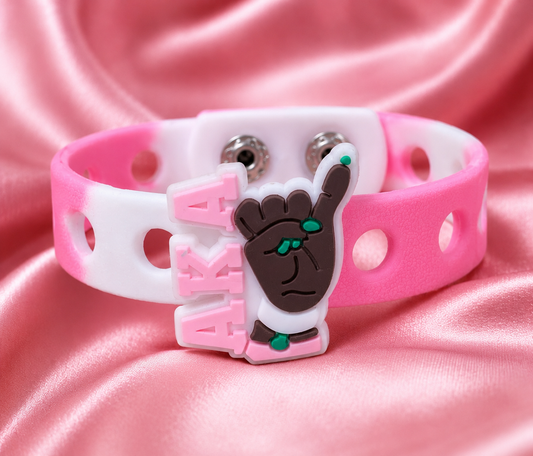 Show your sisterhood pride with the Pinky Promise AKA Bracelet. Featuring a pinky-up charm, pink and white colors, and a comfortable snap-lock design.